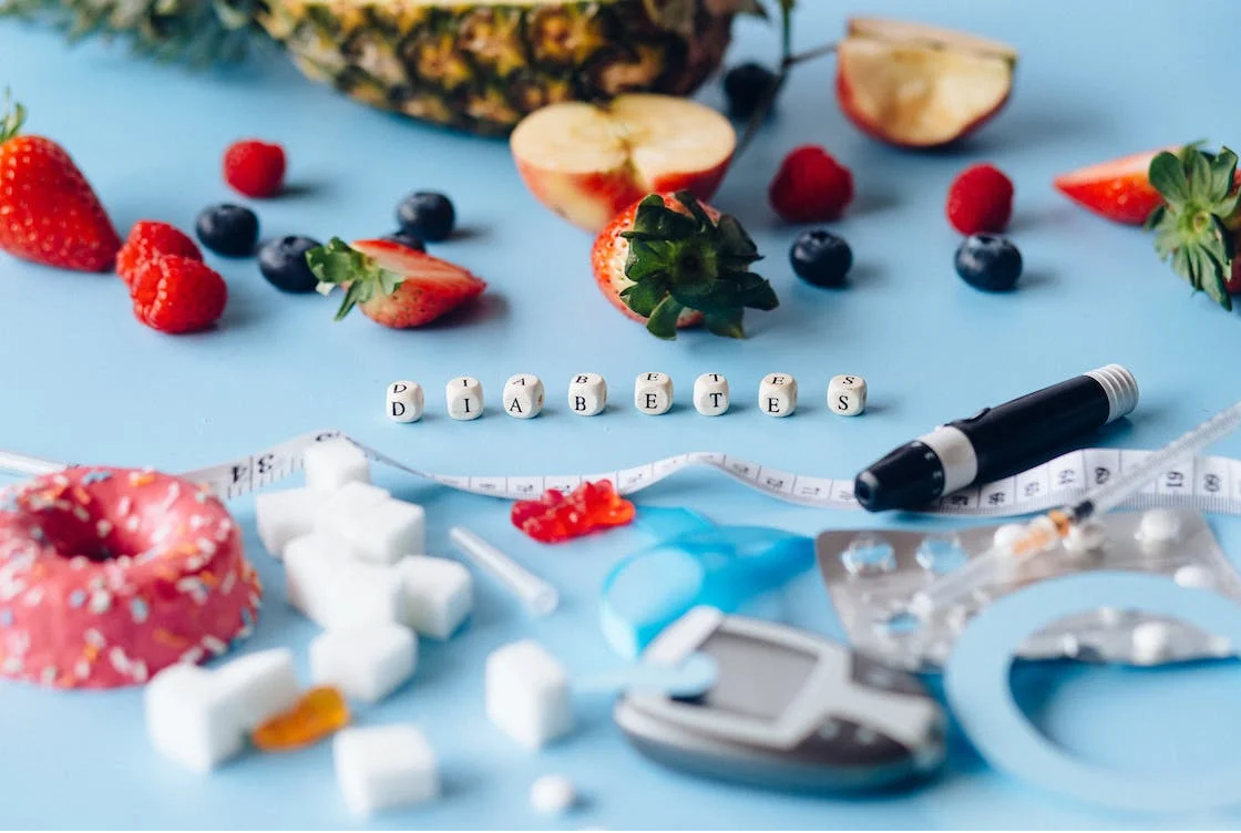 Fruits, a doughnut, sugar cubes and a smart pen laid out on a table